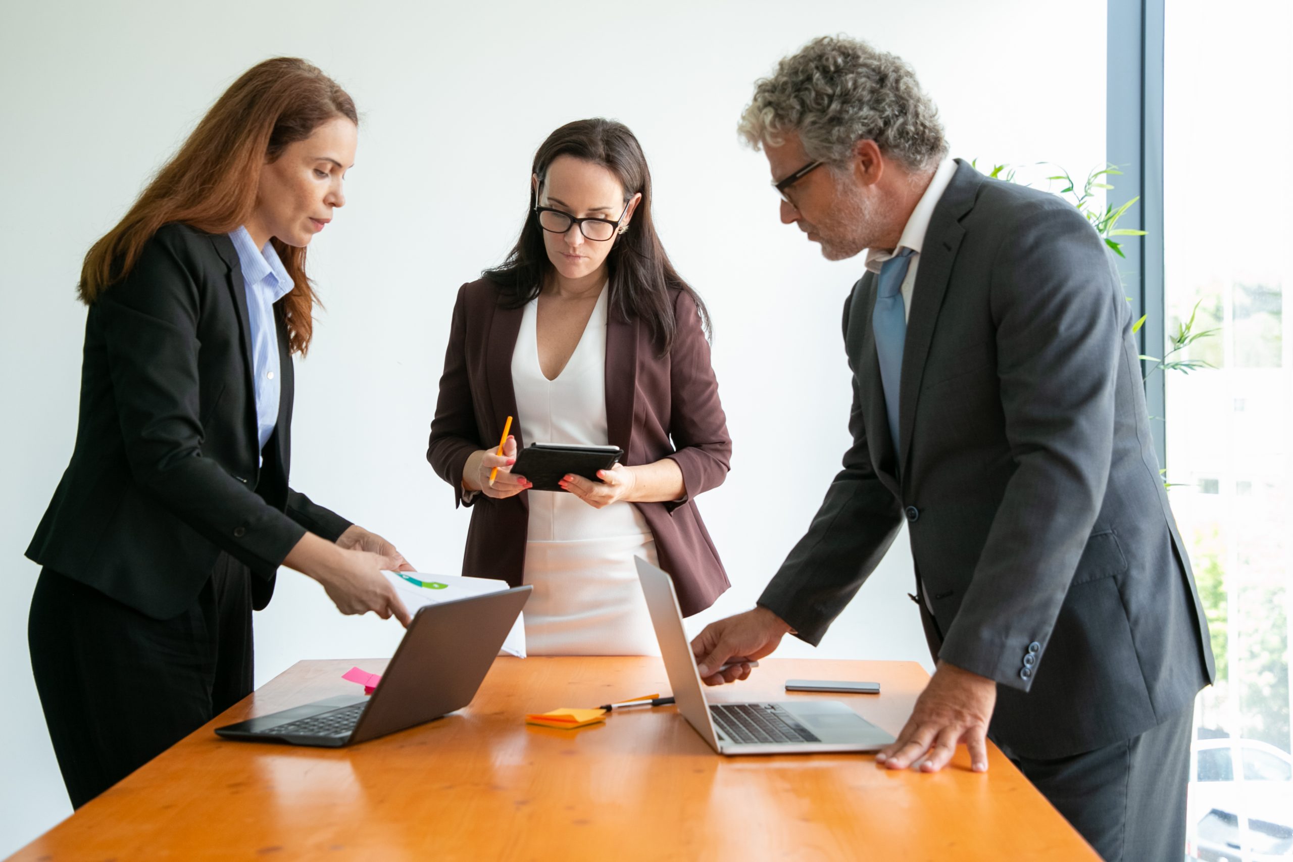 Senior manager in eyeglasses discussing with businesswomen